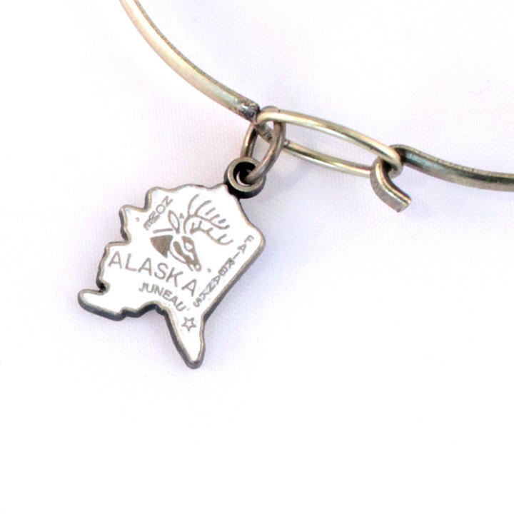 Antique bronze Alaska state charm painted cream and burnished to shiny gold. Map depicts location of Nome, Juneau and Fairbanks and shows a large deer stag.
