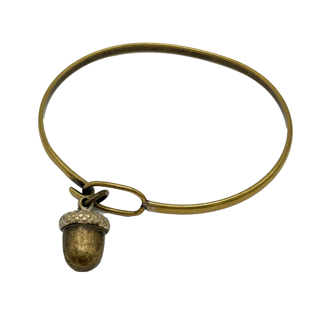 Antique bronze acorn charm with cap painted tan. Shown on a brass bangle bracelet.
