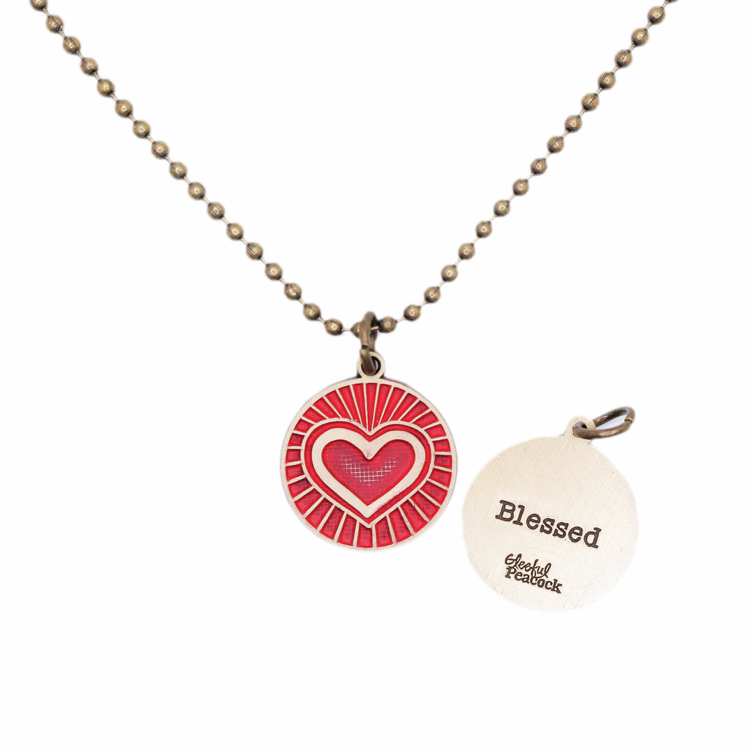 Antique bronze charm painted red and burnished to shiny gold. One side depicts a beaming heart. Reverse side says "Blessed".