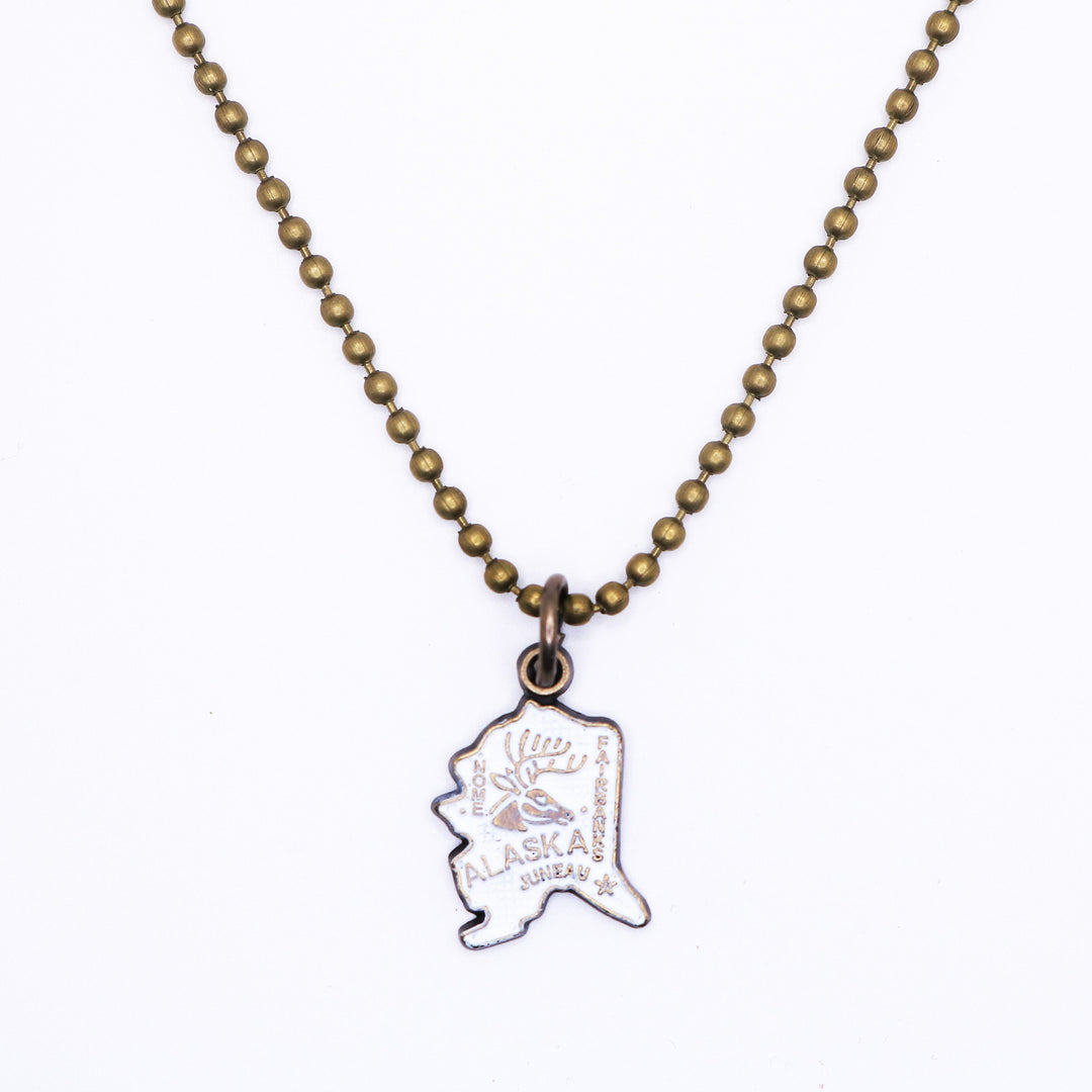 Antique bronze Alaska state charm painted cream and burnished to shiny gold. Map depicts location of Nome, Juneau and Fairbanks and shows a large deer stag.
