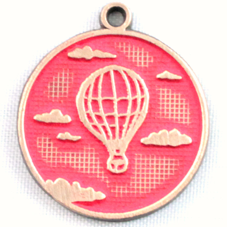Antique bronze charm painted red and burnished to shiny gold. One side depicts a hot air balloon floating in the clouds. Reverse side says "Adventure Awaits".