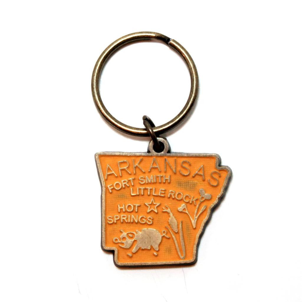 Antique bronze 1 5/8" charm keychain on 1 1/4" keyring. Hand-painted orange. Map depicts location of Fort Smith, Little Rock and Hot Springs. It has agricultural illustrations like a pig and corn.