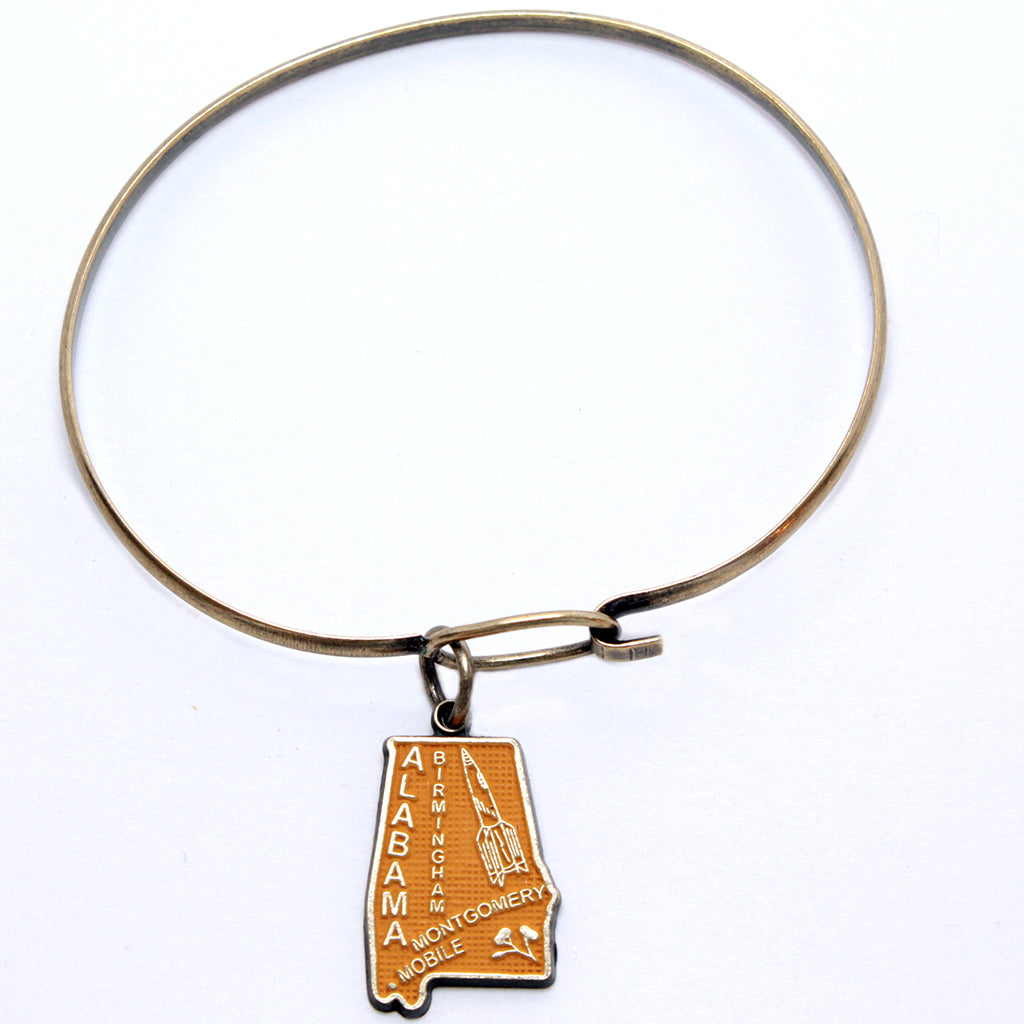 Antique bronze Alabama state charm painted mustard yellow and burnished to shiny gold. Map depicts location of Birmingham, Montgomery and Mobile and shows a rocket ship.