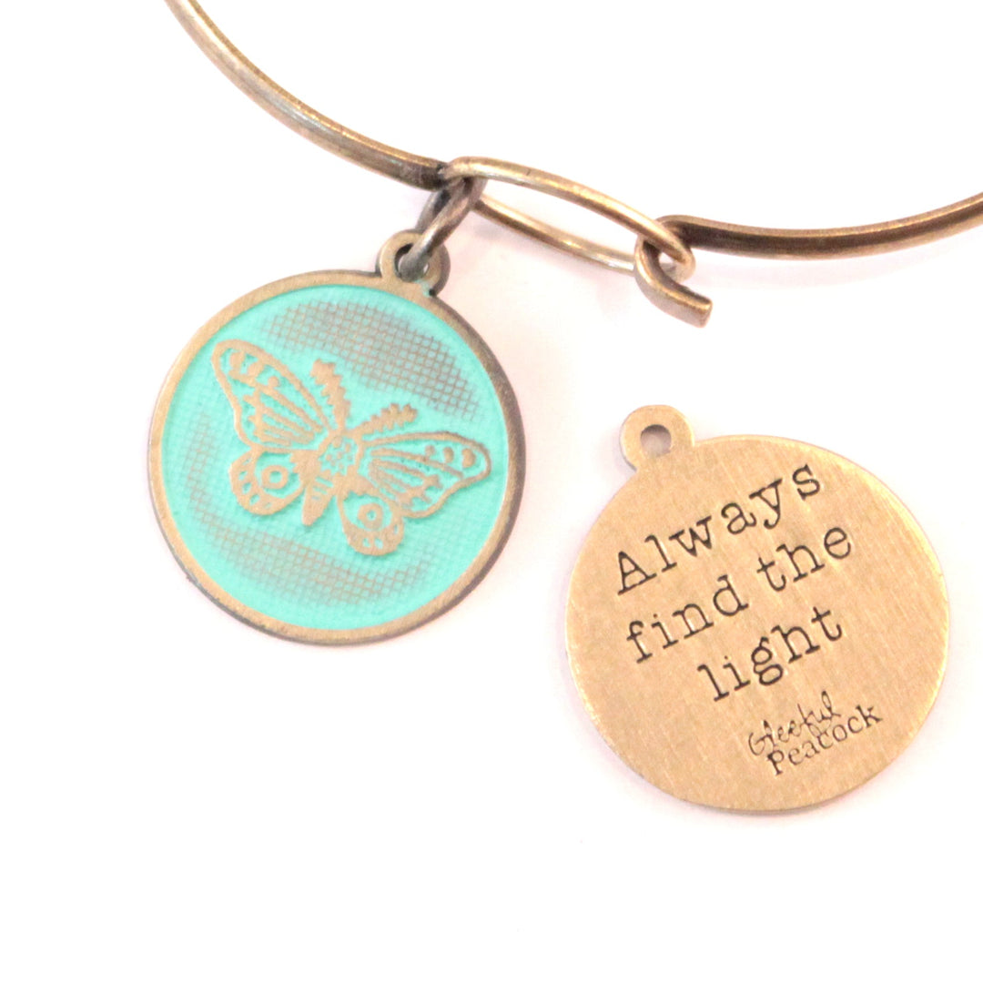 Antique bronze charm painted mint green and burnished to shiny gold. One side depicts a whimsical moth. Reverse side says "Always find the light".