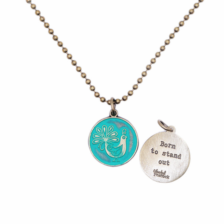 Antique bronze charm painted teal and burnished to shiny gold. One side depicts a whimsical peacock. Reverse side says "Born to stand out".