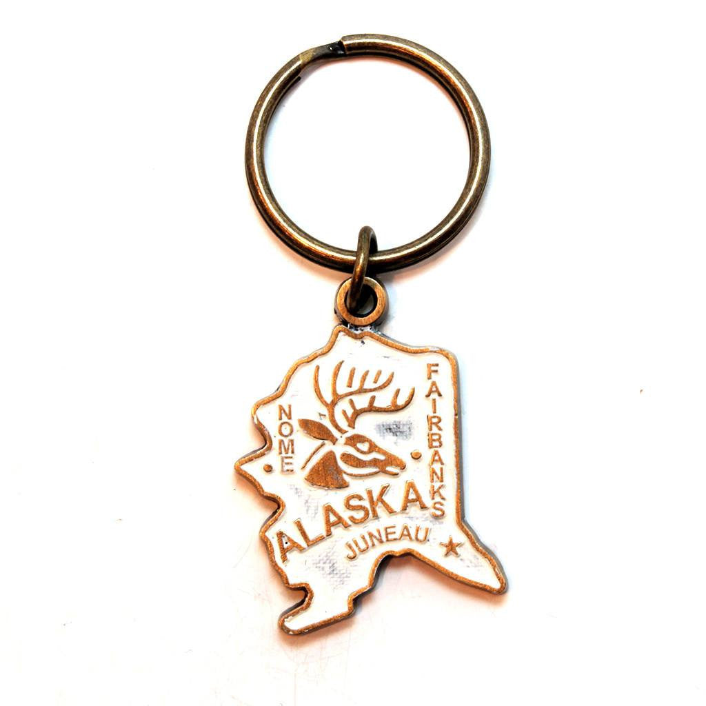 Antique bronze 1 5/8" charm keychain on 1 1/4" keyring. Alaska state charm painted cream and burnished to shiny gold. Map depicts location of Nome, Juneau and Fairbanks and shows a large deer stag.