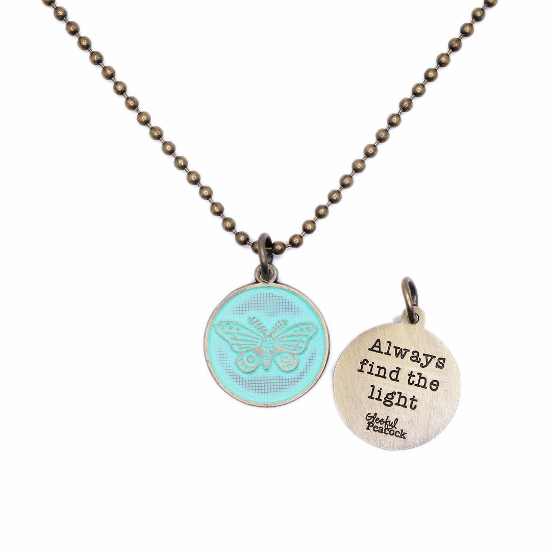 Antique bronze charm painted mint green and burnished to shiny gold. One side depicts a whimsical moth. Reverse side says "Always find the light".