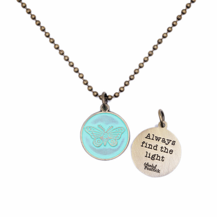 Antique bronze charm painted mint green and burnished to shiny gold. One side depicts a whimsical moth. Reverse side says "Always find the light".