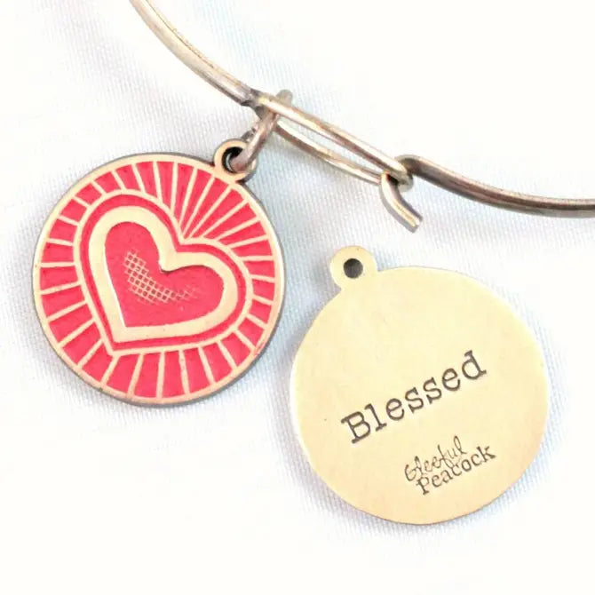 Antique bronze charm painted red and burnished to shiny gold. One side depicts a beaming heart. Reverse side says "Blessed".