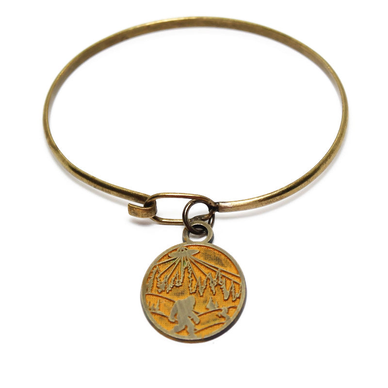 Whimsical charm with illustration of bigfoot, a UFO and a unicorn. The reverse says "Believe in Yourself." Antique bronze painted yellow and burnished.