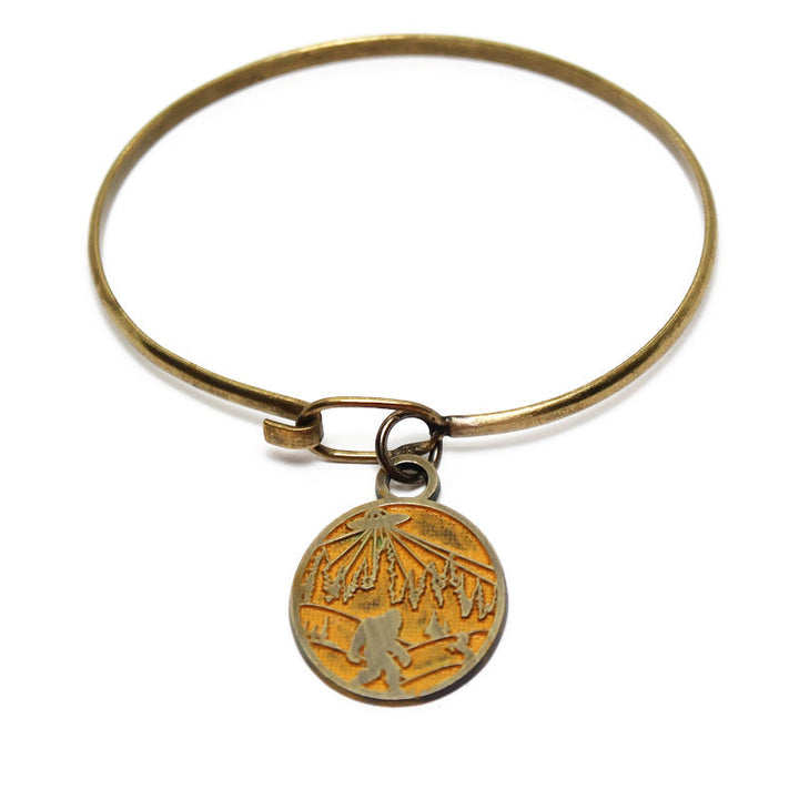Whimsical charm with illustration of bigfoot, a UFO and a unicorn. The reverse says "Believe in Yourself." Antique bronze painted yellow and burnished.