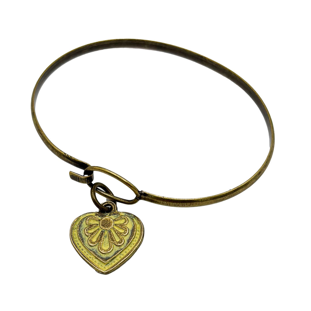 Antique bronze charm painted light yellow and burnished to shiny gold. Graphic details mimic a blooming flower. Shown on a brass hook bracelet.