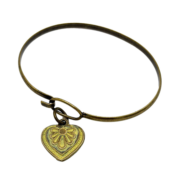 Antique bronze charm painted light yellow and burnished to shiny gold. Graphic details mimic a blooming flower. Shown on a brass hook bracelet.