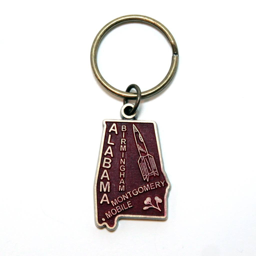 Antique bronze 1 1/4" charm keychain on 1 1/4" keyring. Alabama state charm painted dark red and burnished to shiny gold. Map depicts location of Birmingham, Montgomery and Mobile and shows a rocket ship.