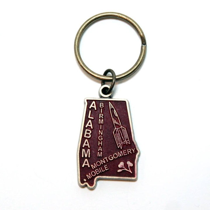 Antique bronze 1 1/4" charm keychain on 1 1/4" keyring. Alabama state charm painted dark red and burnished to shiny gold. Map depicts location of Birmingham, Montgomery and Mobile and shows a rocket ship.