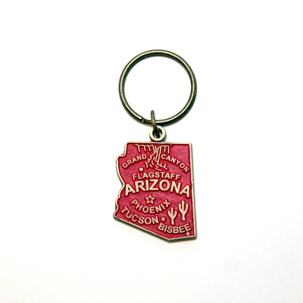 Antique bronze 1 5/8" charm keychain on 1 1/4" keyring. Alaska state charm painted red and burnished to shiny gold. Map depicts location of Flagstaff, Phoenix, Tucson and Bisbee. Illustrated with the Grand Canyon and Saguaro cacti.